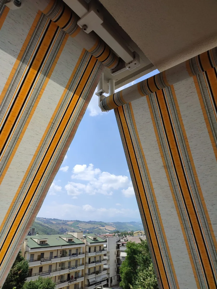 Tenda da sole a strisce colorate su terrazzo con vista sulle colline abruzzesi — IS Metal srl Teramo